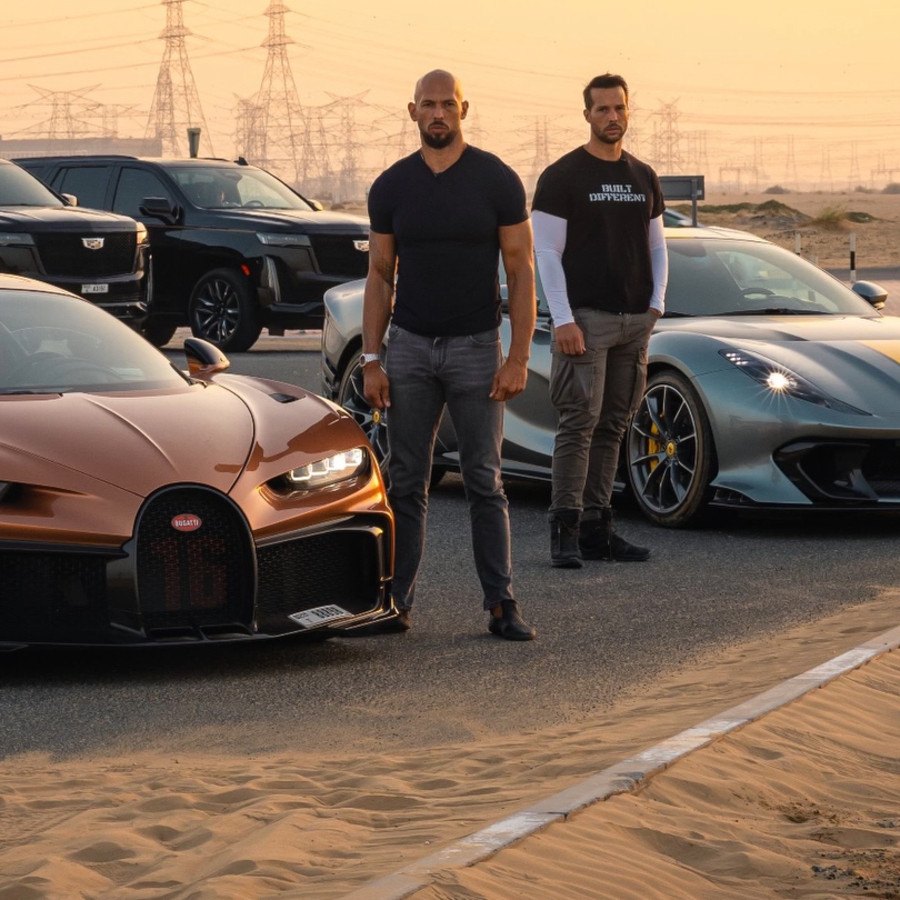 Andrew and Tristan Tate standing beside a bronze Bugatti Chiron and a Ferrari